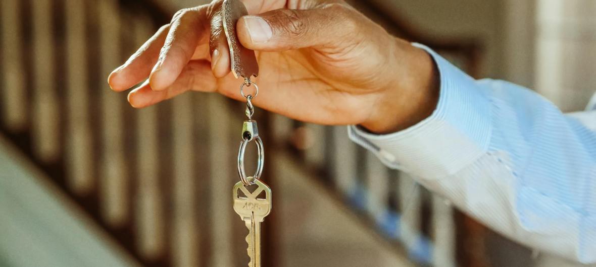 person holding a silver keychain with a key